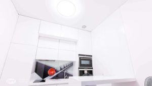 Minimalistycznie urządzona kuchnia w kolorze białym z czarno-białą grafiką nad blatem